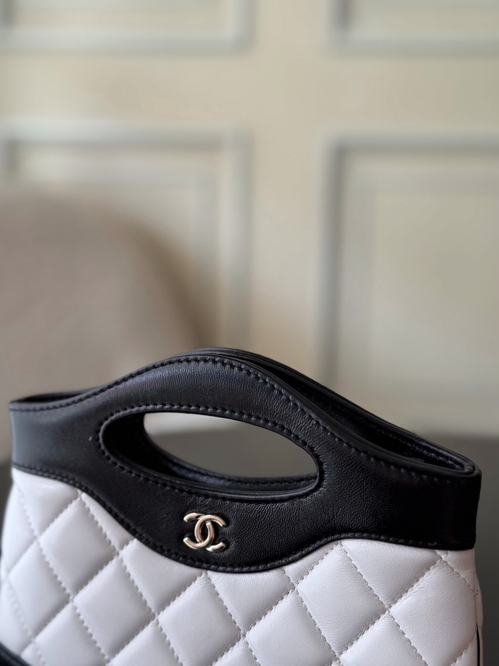 Chanel quilted mini handbag, side view with oval handle and CC logo