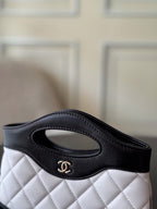 Chanel quilted mini handbag, side view with oval handle and CC logo