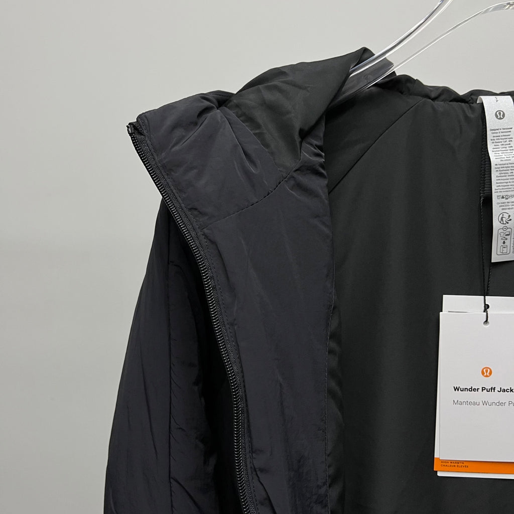 Black puffer jacket side view with zipper and hanging tags