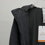 Black puffer jacket side view with zipper and hanging tags