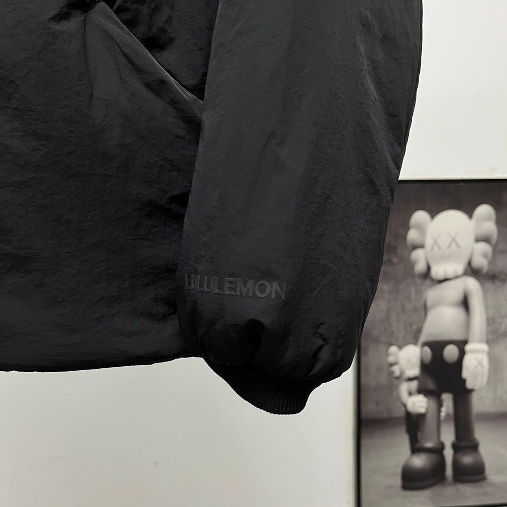 Black puffer jacket sleeve cuff with small text print
