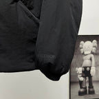 Black puffer jacket sleeve cuff with small text print