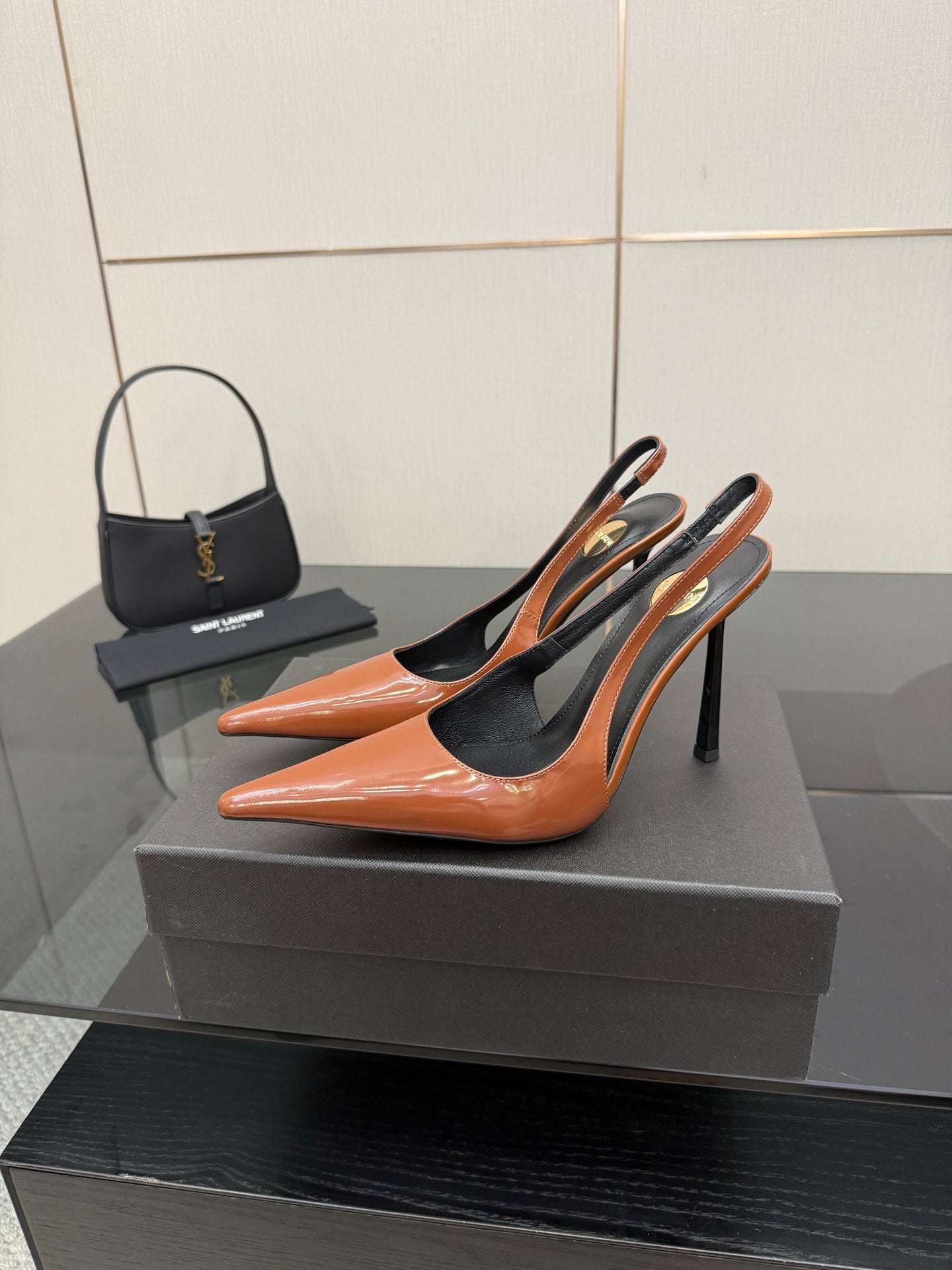 Ladies' YSL orange-and-black pointed-toe pumps on display with high stiletto heels