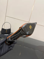 Ladies' YSL black pointed-toe pump with orange trim, close-up view