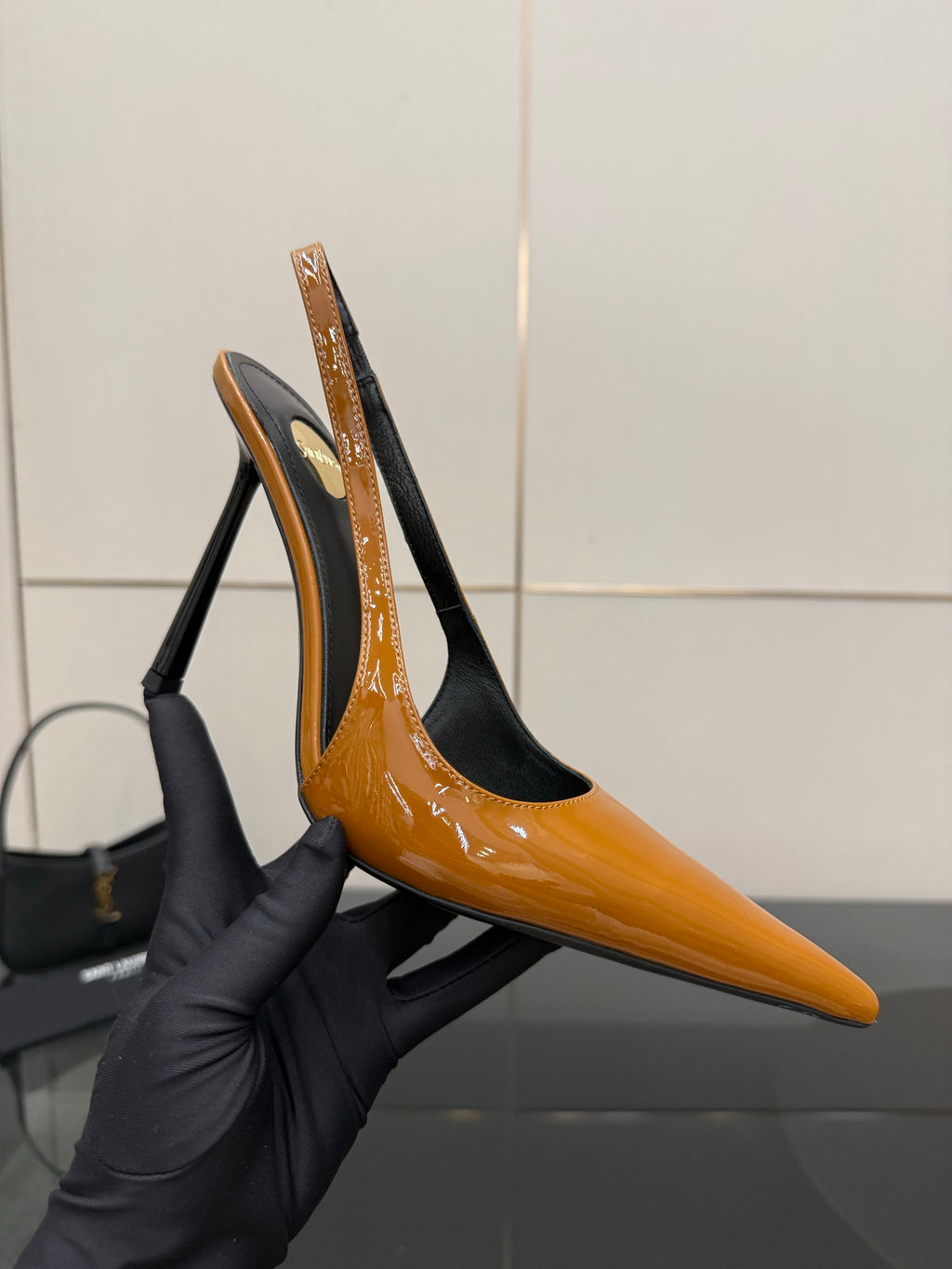 Women's orange patent slingback pump with black back and tall stiletto heel.