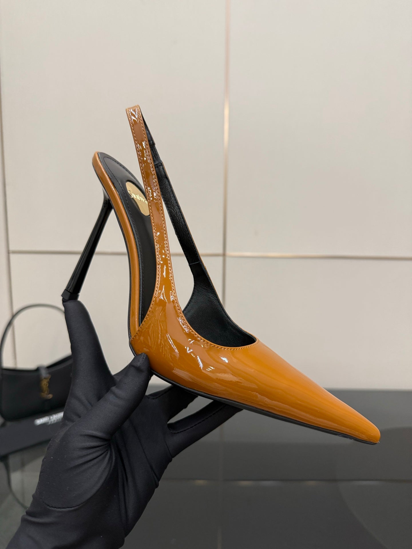 Women's orange patent slingback pump with black back and tall stiletto heel.
