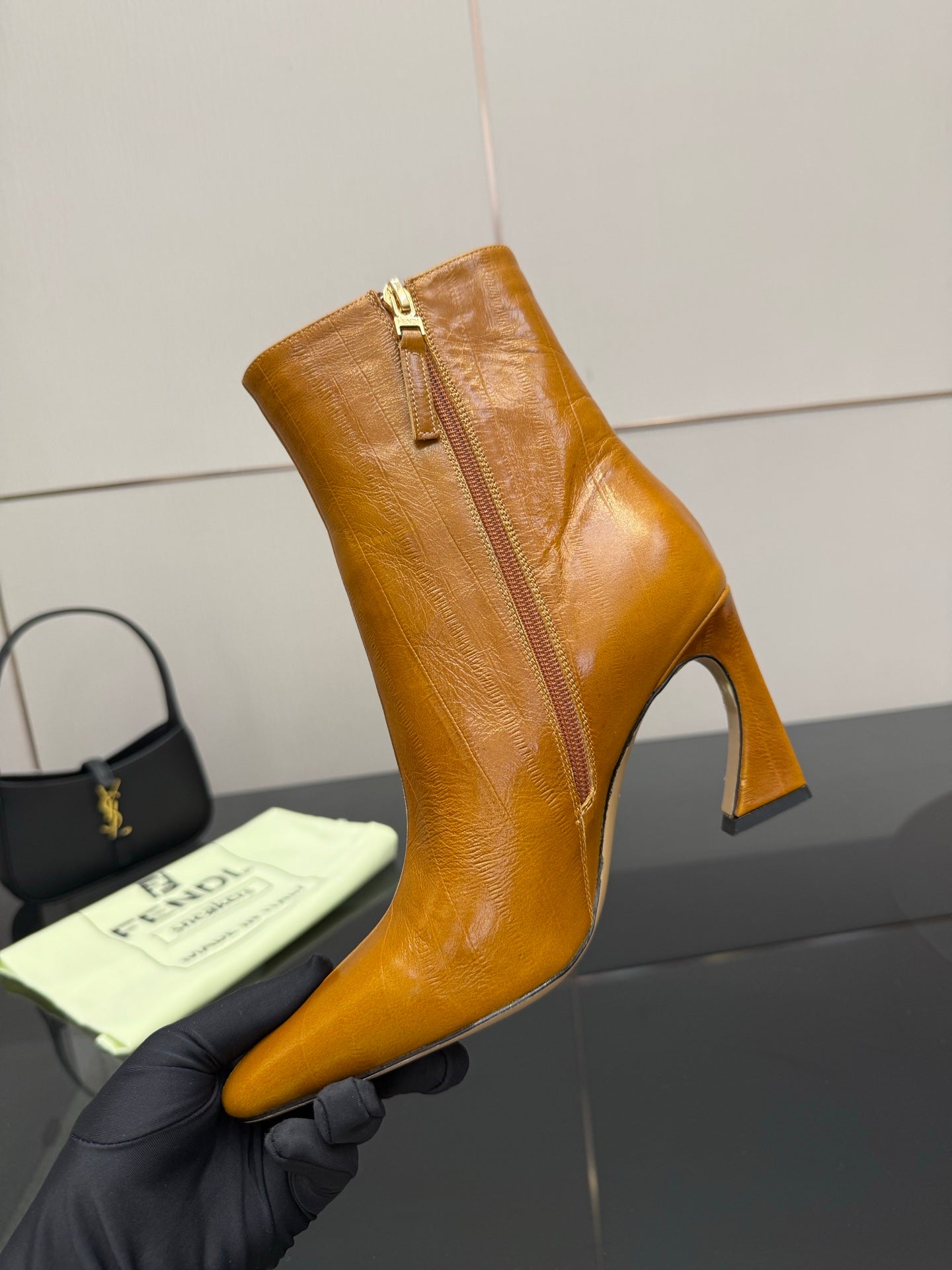 Tan leather ankle boot with high heel, pointed toe, and visible side zipper