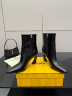 Pair of women’s black heeled ankle boots with pointed toes and gold zipper hardware