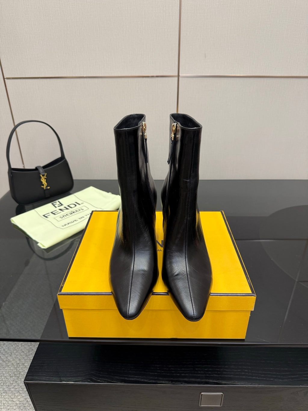 Women’s black leather heeled ankle boots with gold zipper pull and pointed toe
