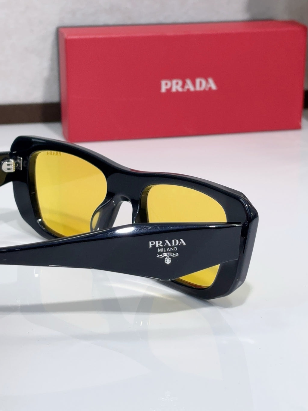 Prada sunglasses close-up with yellow tinted lenses and logo on temple