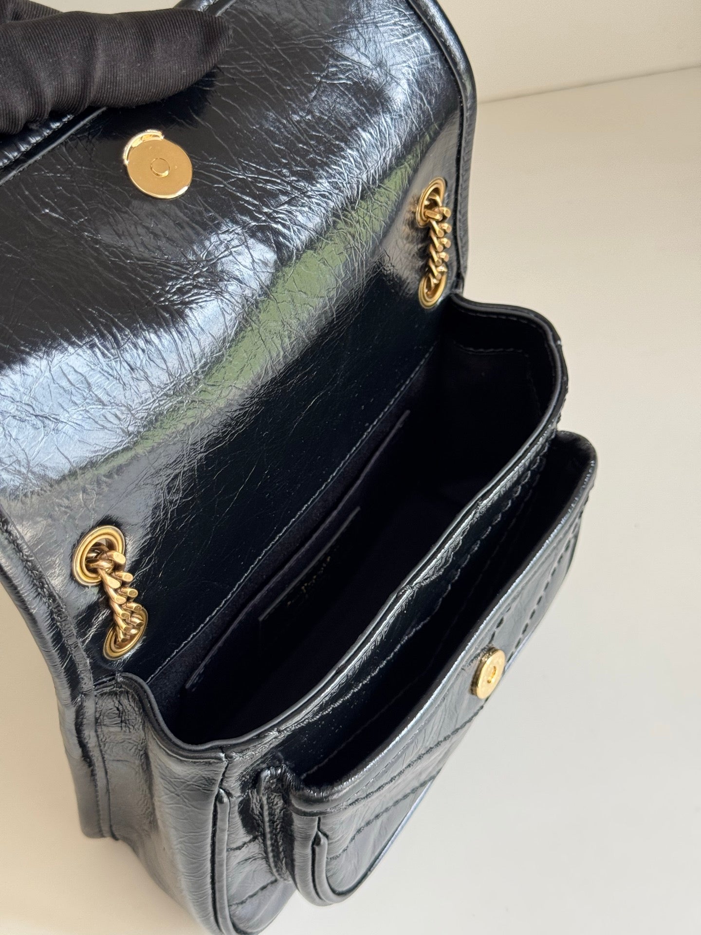 YSL dark leather mini bag open view with gold button, interior lining and chain