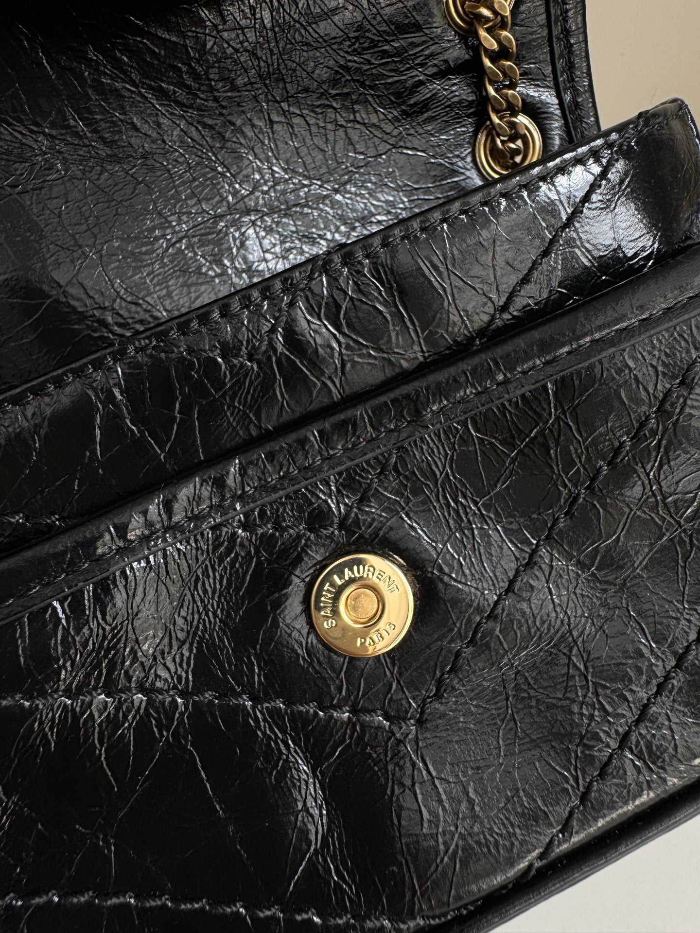 YSL dark leather flap bag with round gold logo medallion on front panel