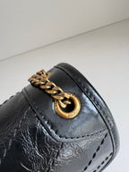 YSL dark leather bag detail with gold ring clasp, stitched flap and textured finish