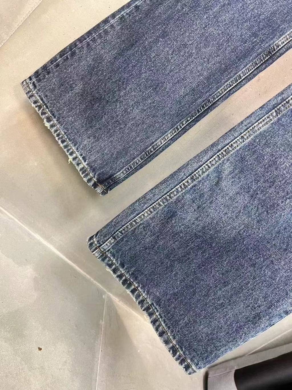 Balenciaga denim pants hems detail, faded blue wash with visible stitching