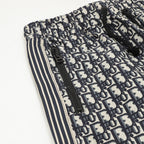 Pants side close-up with Dior monogram print, zipper detail, and striped trim