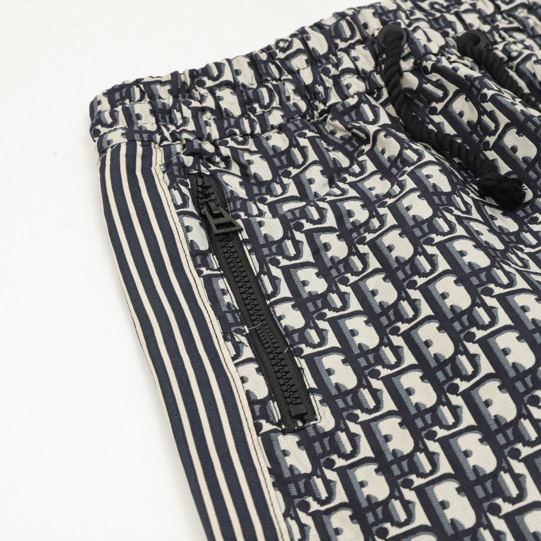 Pants side close-up with Dior monogram print, zipper detail, and striped trim