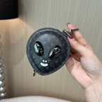 Louis Vuitton round zip pouch with monogram texture and cat-face charm, held by hand