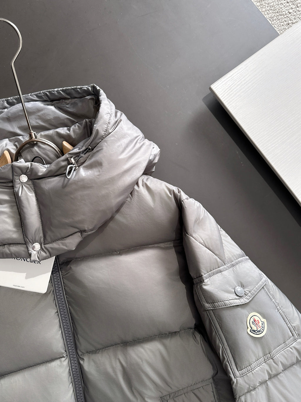 Gray puffer jacket chest with front zipper and small round logo patch