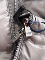 Gray puffer jacket zipper with metal pulls and inner fabric label