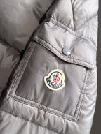Gray puffer jacket sleeve with round logo patch near cuff