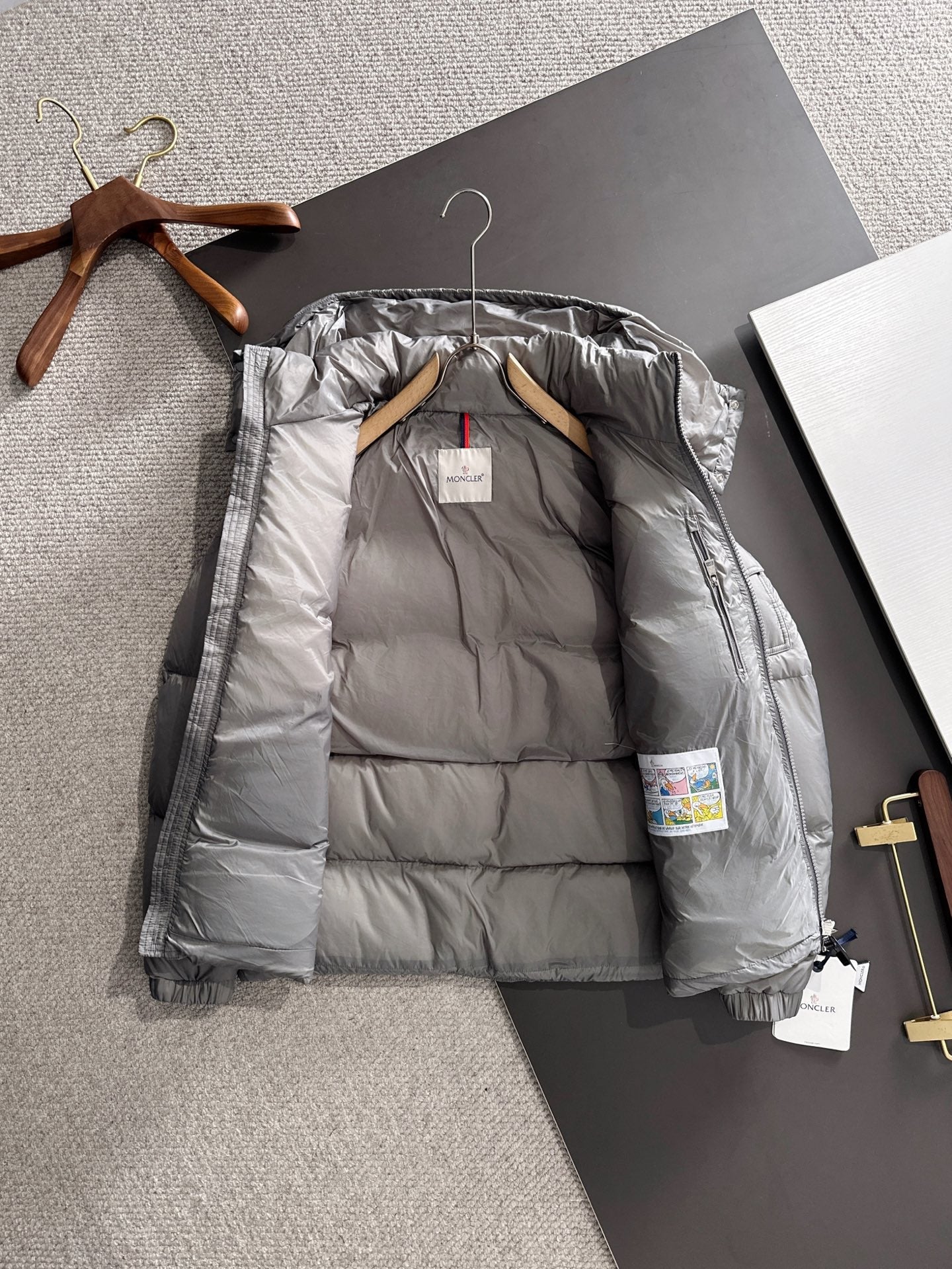 Gray hooded puffer jacket laid open showing inner lining and front zipper