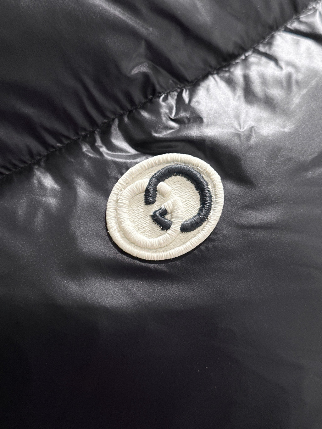 Gucci logo button patch on black padded jacket panel