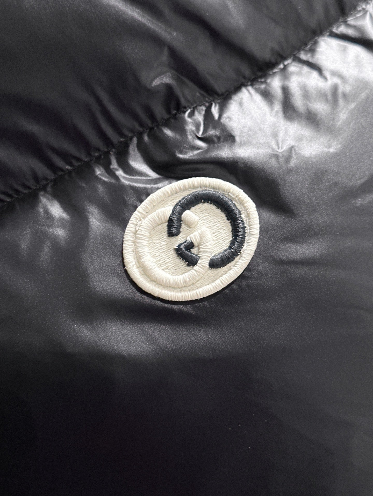 Gucci logo button patch on black padded jacket panel