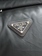 Prada triangular logo patch on dark gray puffer vest fabric