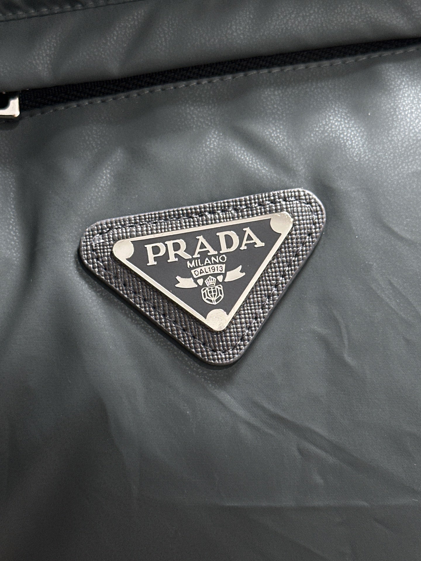 Prada triangular logo patch on dark gray puffer vest fabric
