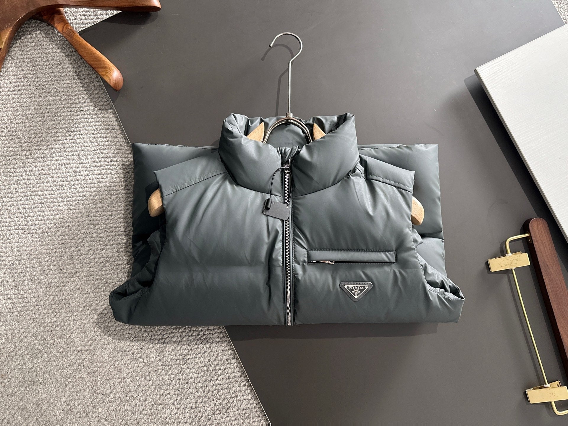 Prada dark gray quilted puffer vest with front zipper, hanging on hanger