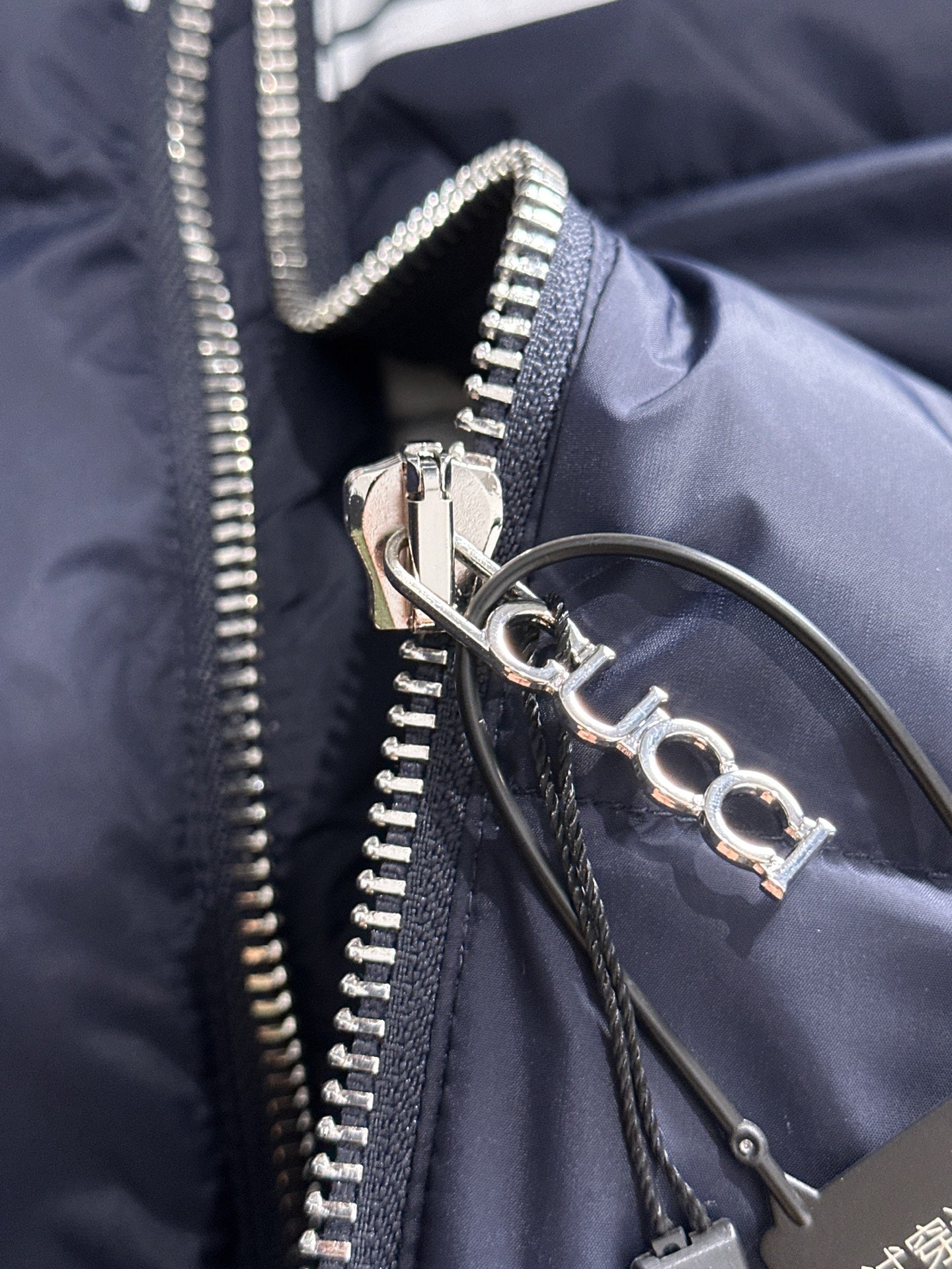 Gucci puffer jacket zipper pull and snap ring detail on navy fabric