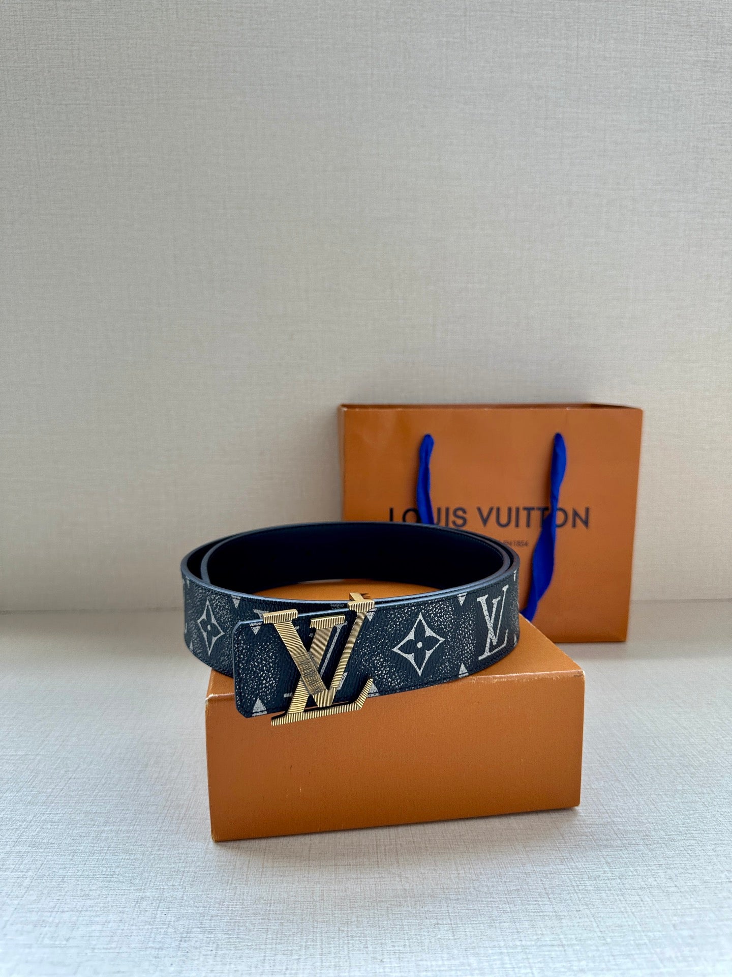 Monogram belt on box, dark patterned strap with gold-tone LV buckle