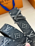 Monogram belt with textured dark strap and gold-tone buckle, angled view