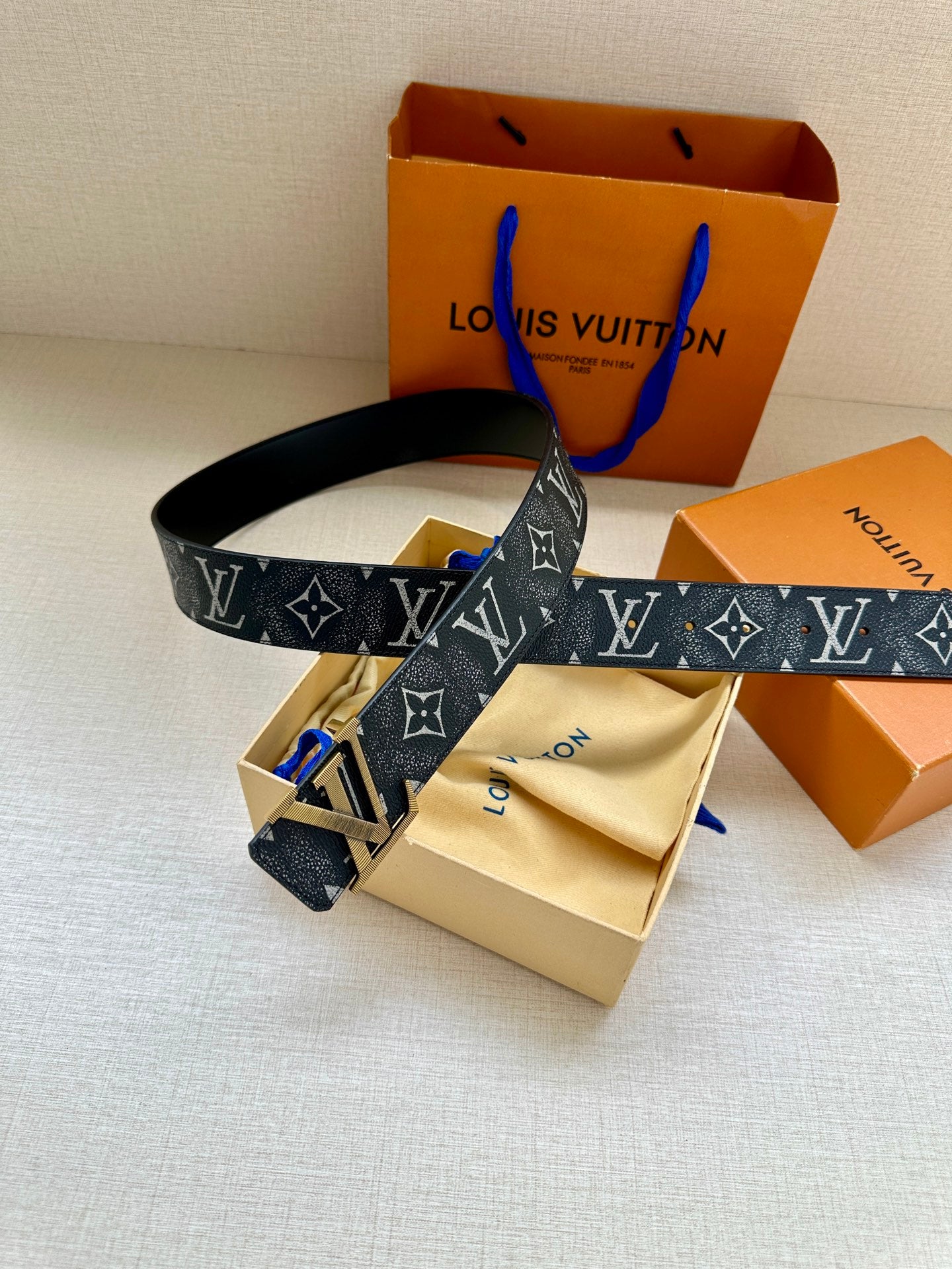 Monogram belt with gold-tone buckle and dark patterned strap with accessories