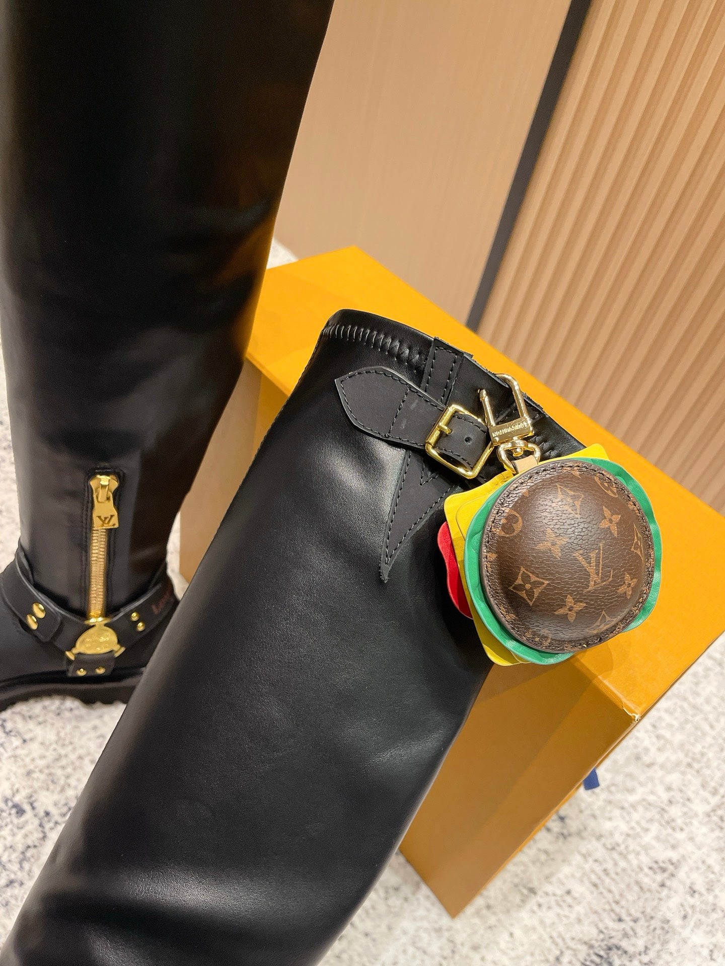 Louis Vuitton unisex black leather knee-high boot close-up of gold zipper and LV charm