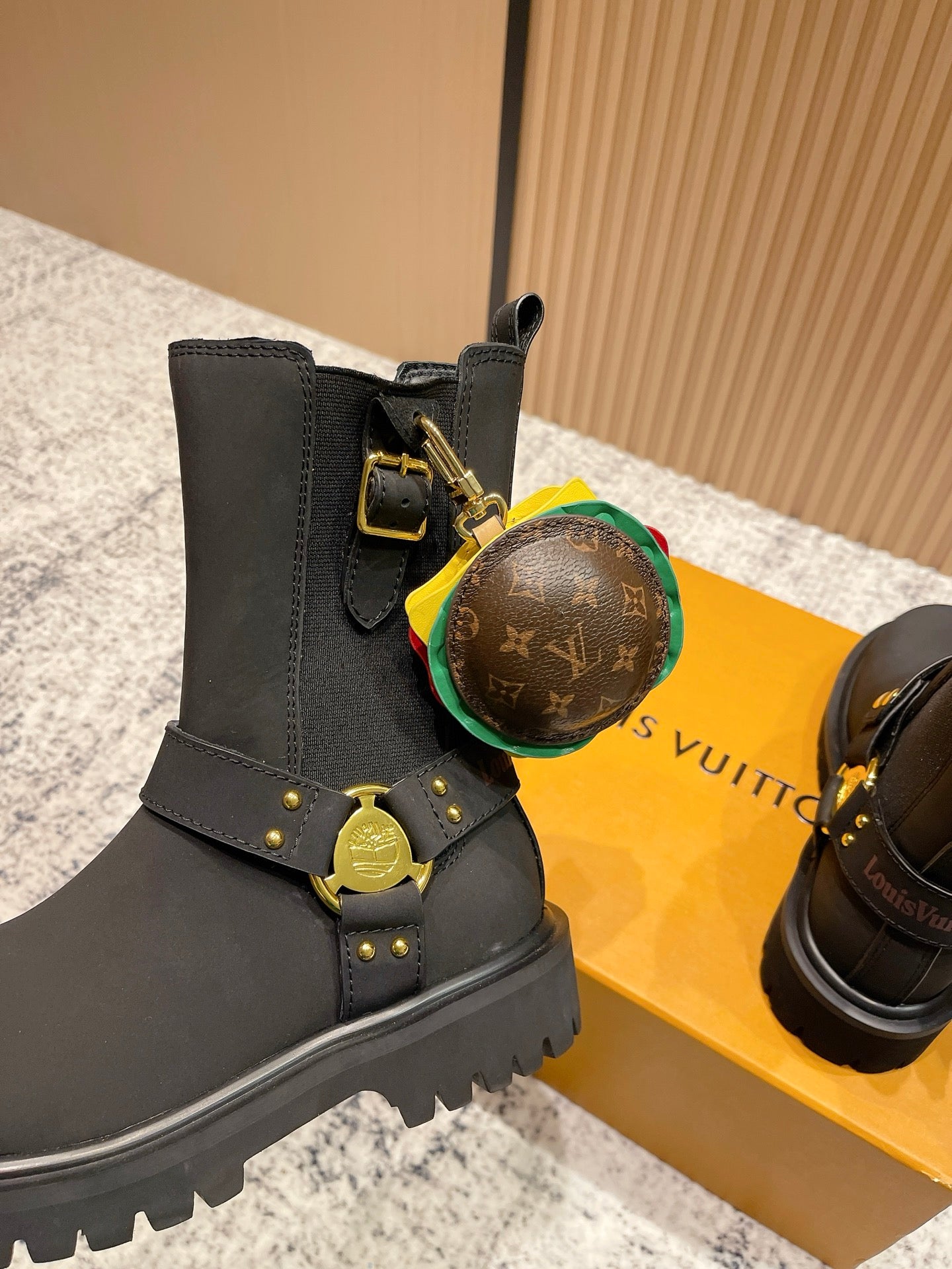 Louis Vuitton black ankle boots with round monogram charm and gold strap hardware, unisex