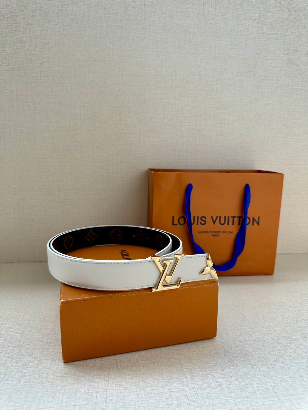 White leather belt with dark monogram reverse and gold buckle detail