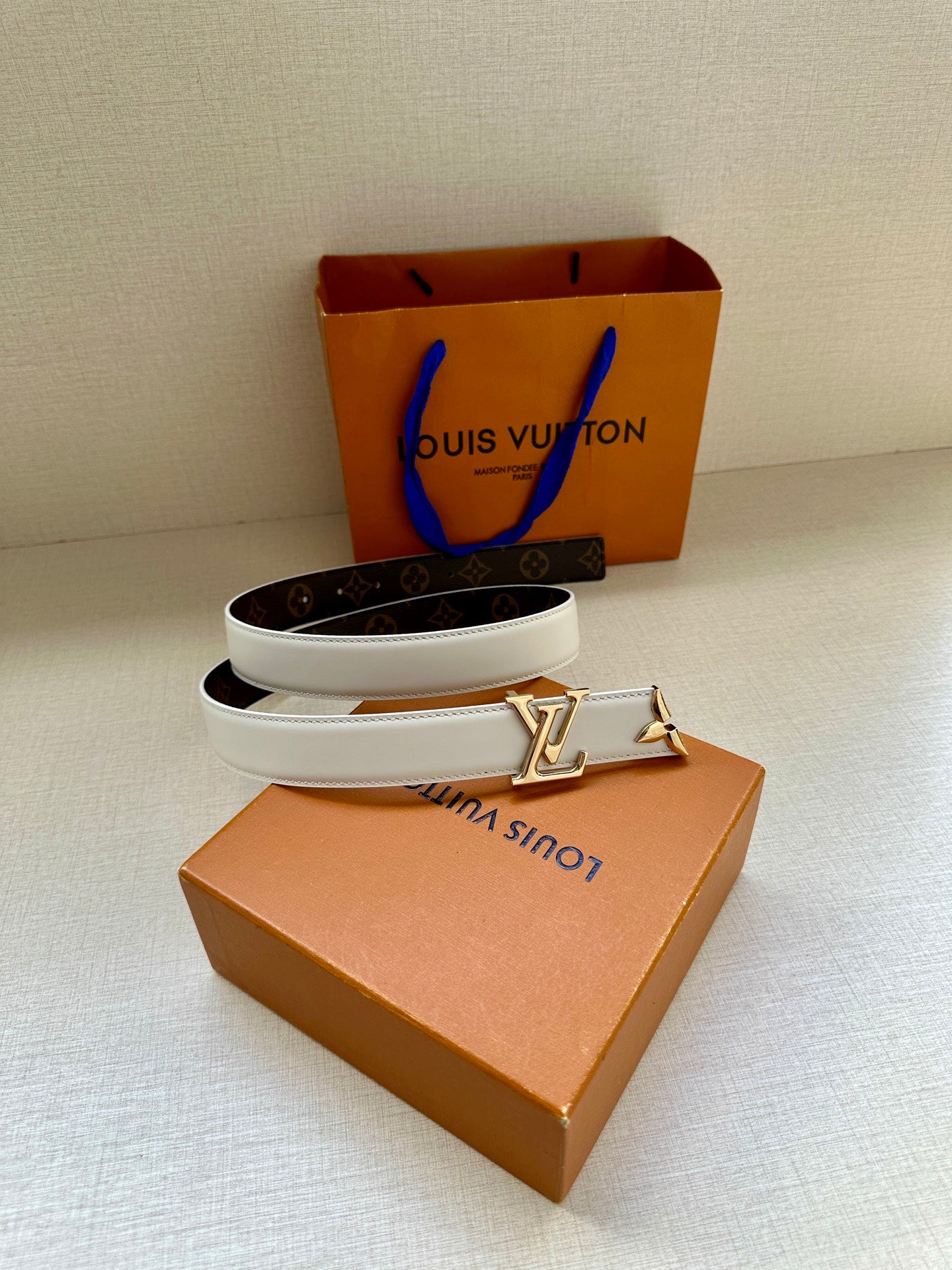 White leather belt with gold buckle and dark monogram band