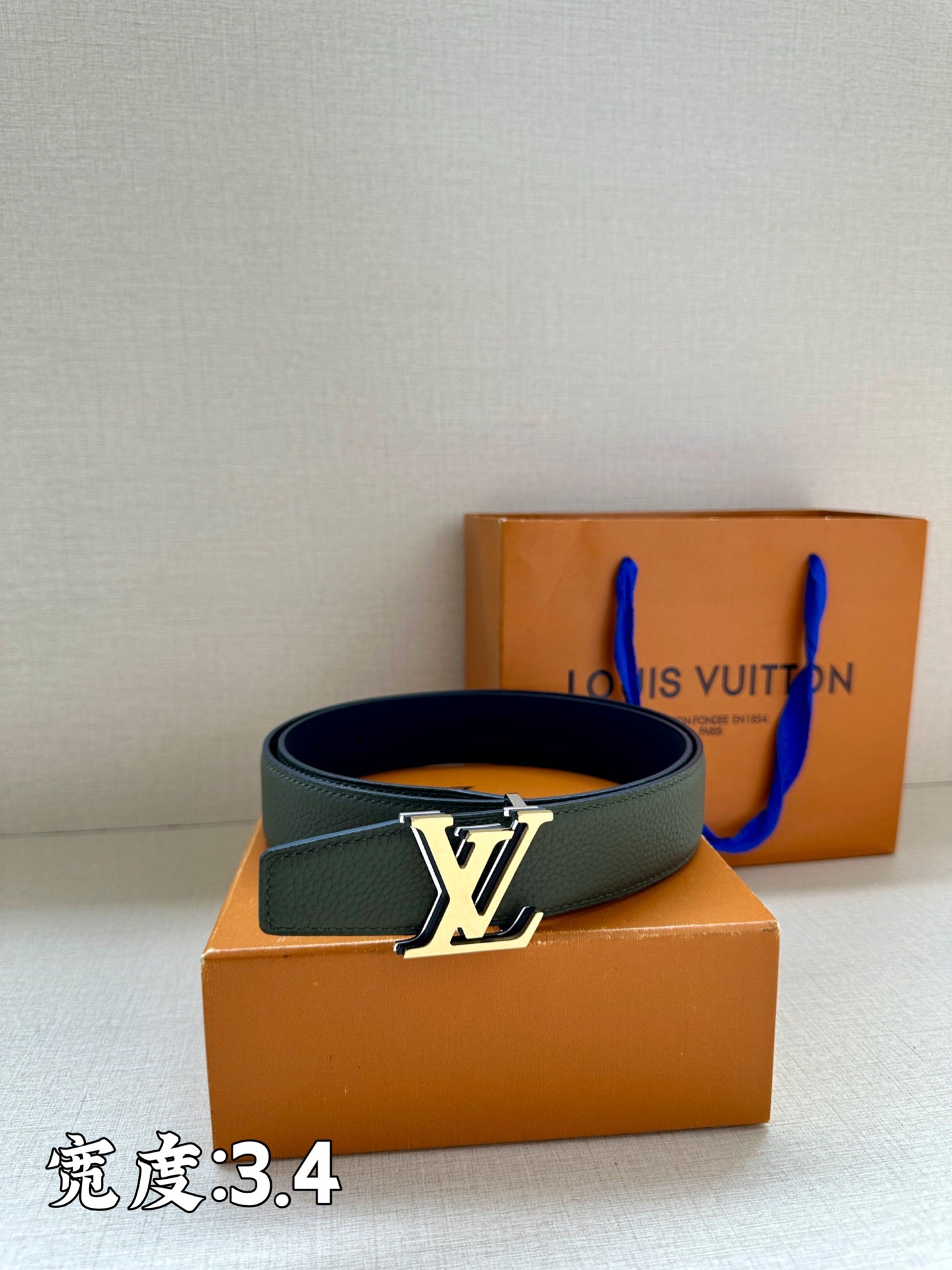 Louis Vuitton leather belt in dark green with silver LV buckle on a folded strap.
