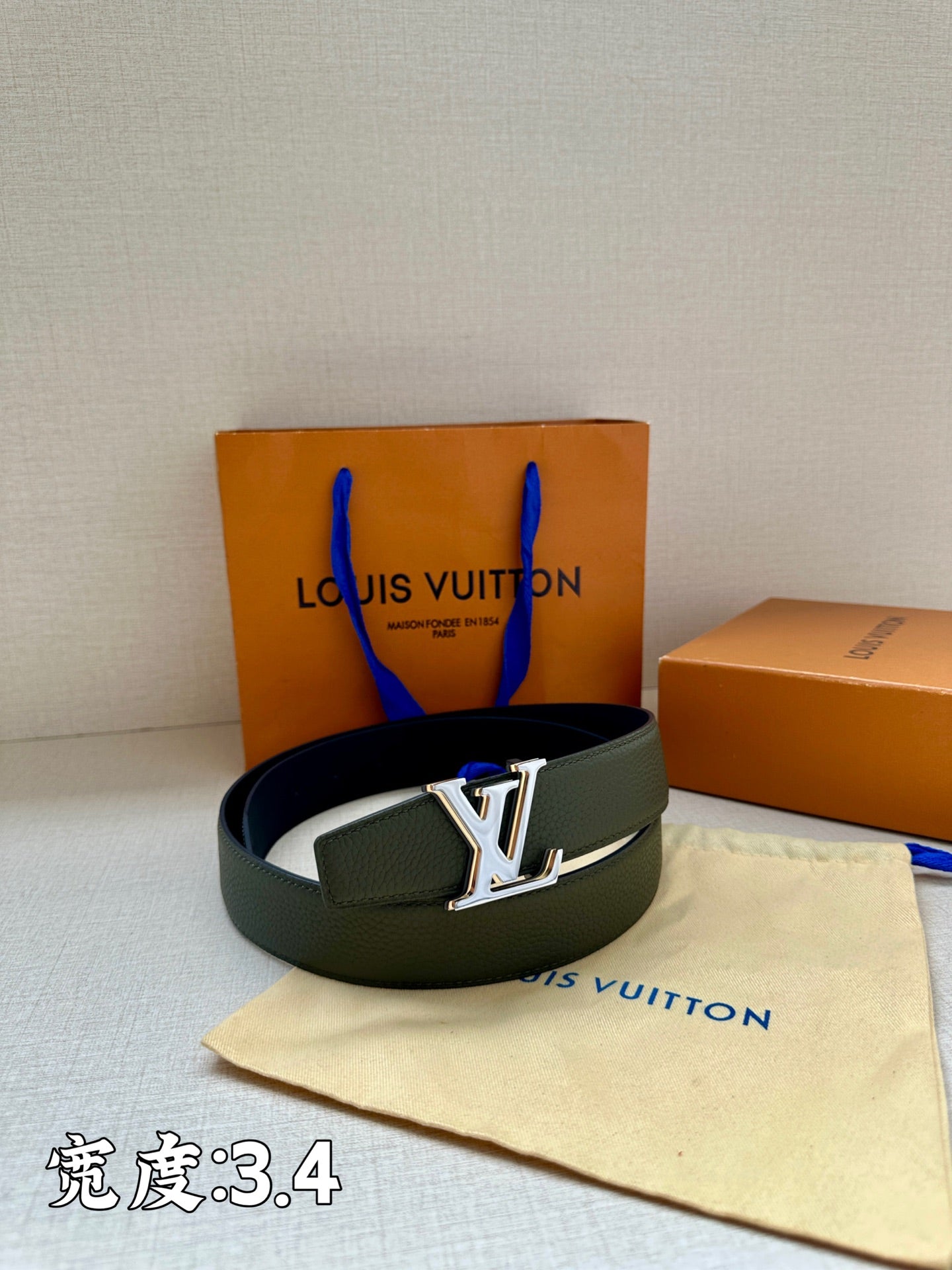 Louis Vuitton leather belt in dark green with silver LV buckle on folded strap.