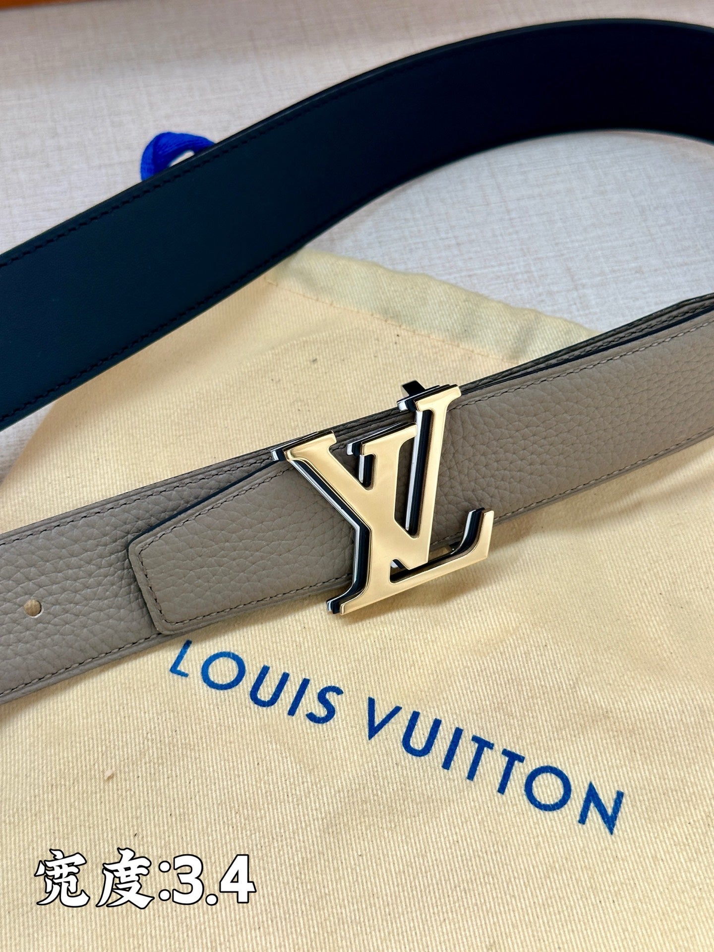 Grey leather belt with gold-tone LV buckle, close-up view of strap