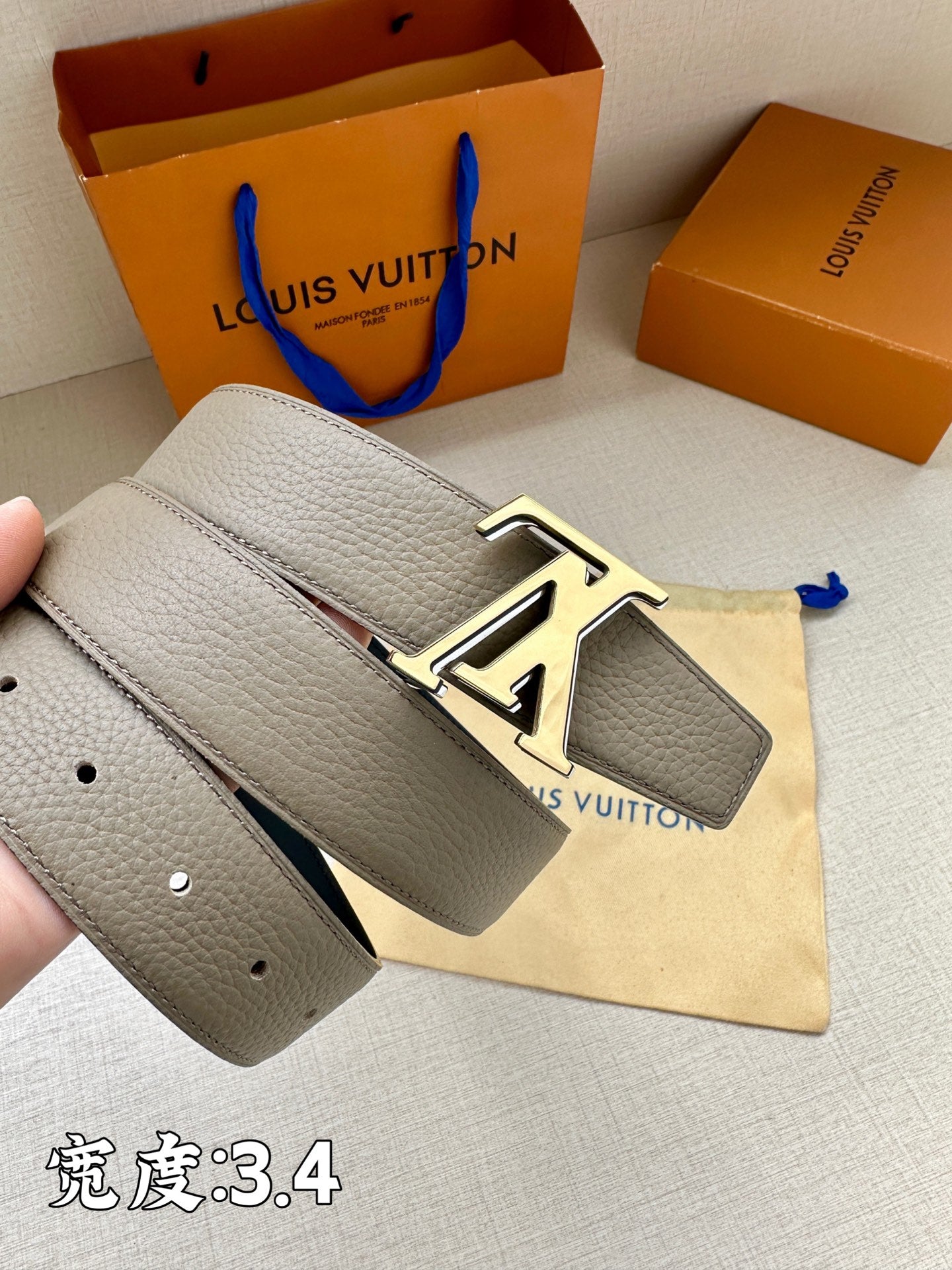 Grey leather belt with gold-tone LV buckle and perforated strap end
