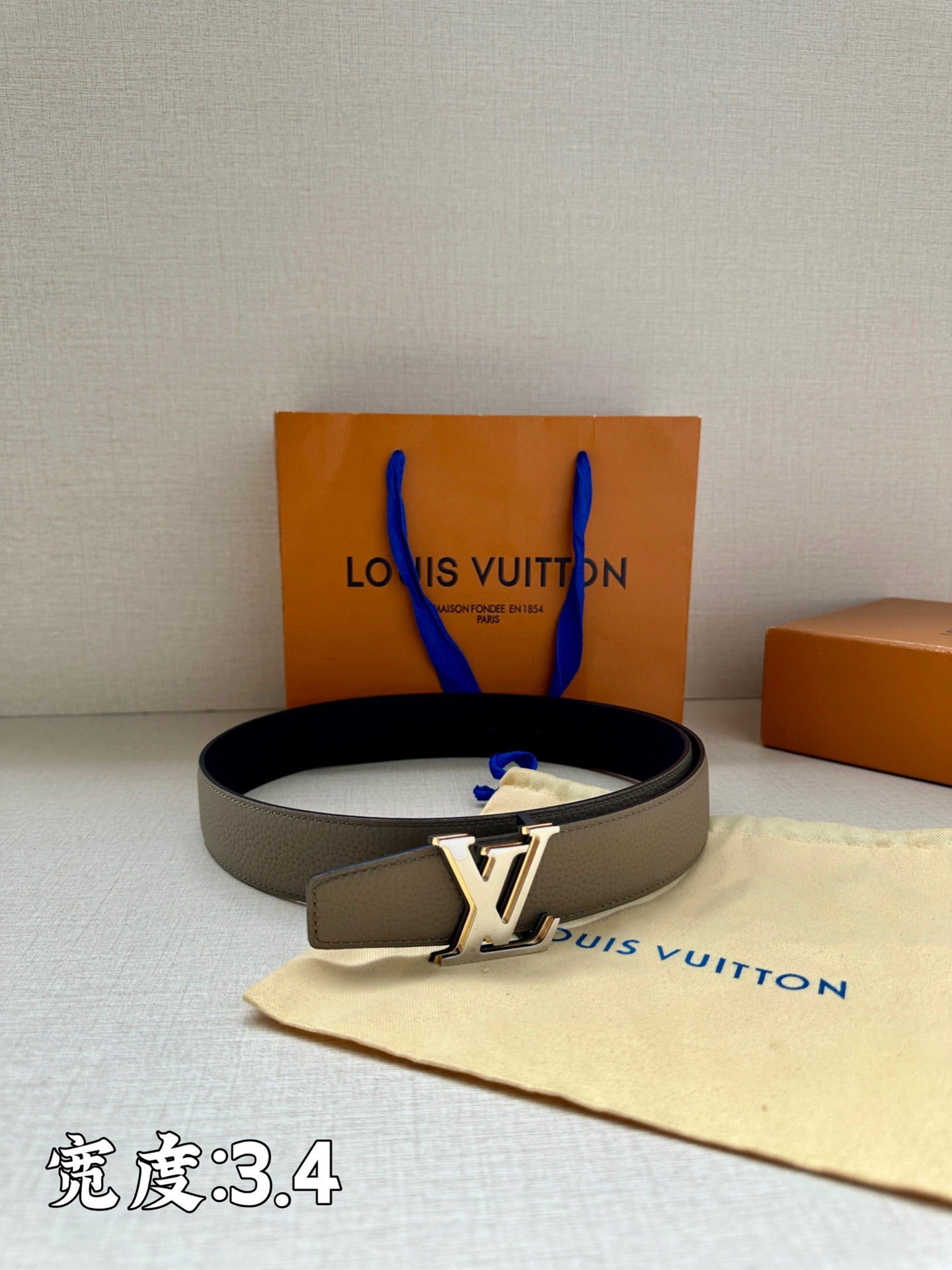 Grey leather belt with gold-tone LV buckle and perforated strap end