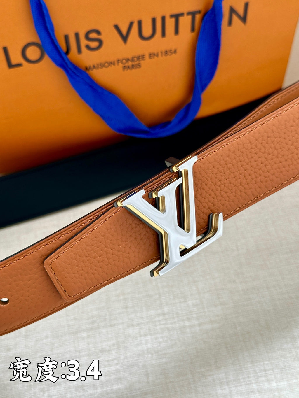 Brown leather belt close-up with gold-tone LV buckle