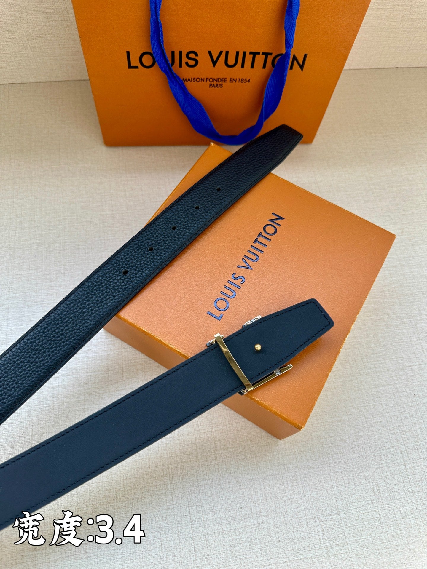 Louis Vuitton belt with textured dark blue leather and gold buckle, laid diagonally