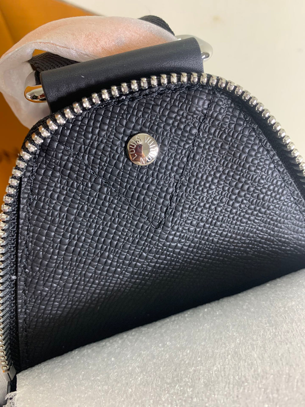 Louis Vuitton bag top zipper and textured finish with small round logo medallion