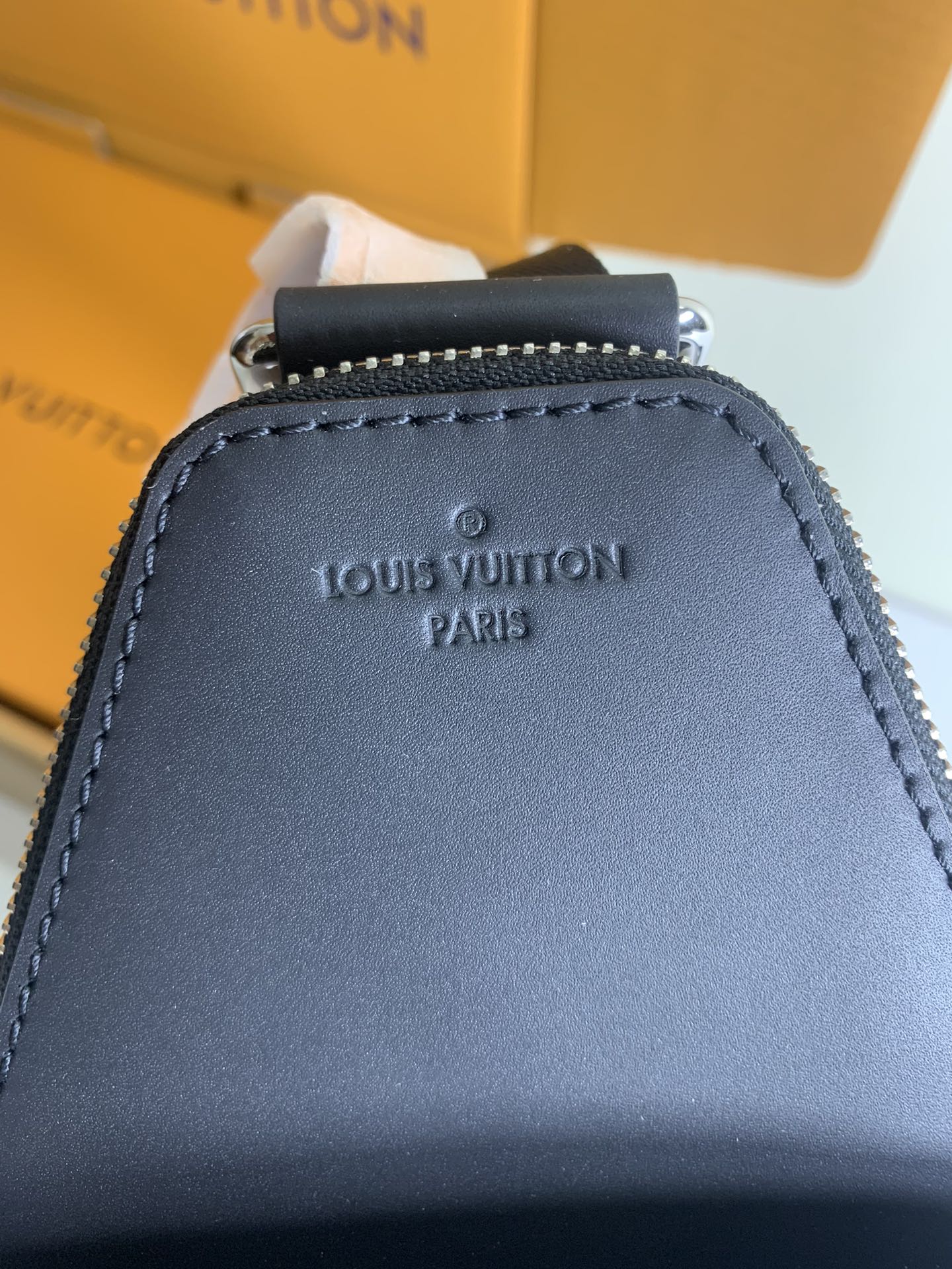 Louis Vuitton logo detail on dark leather trim with zipper top on bag