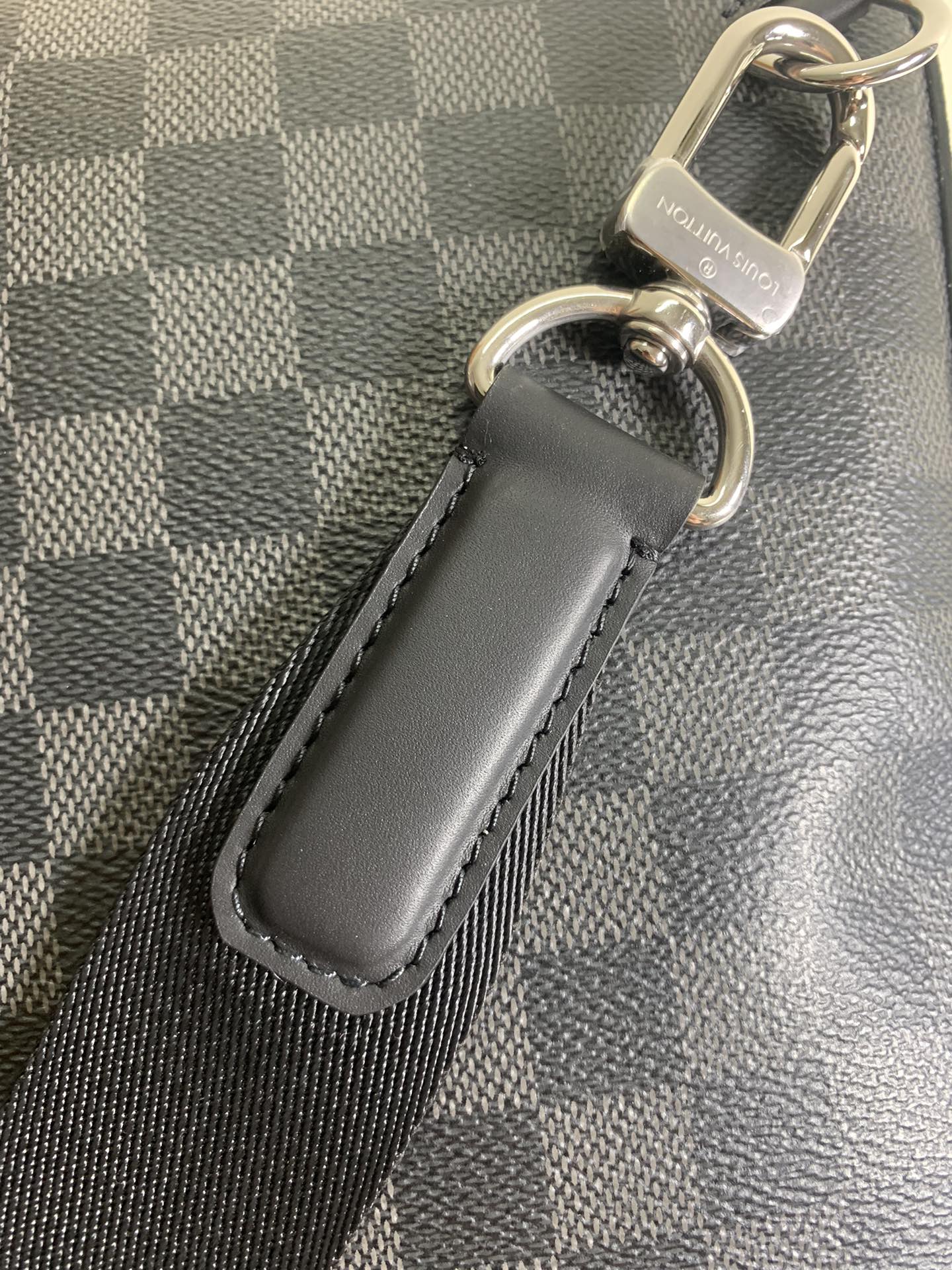 Louis Vuitton bag strap attachment with dark leather tab and metal rings