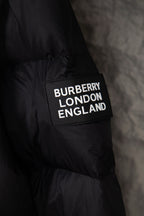 Black puffer jacket sleeve with “BURBERRY LONDON ENGLAND” patch label