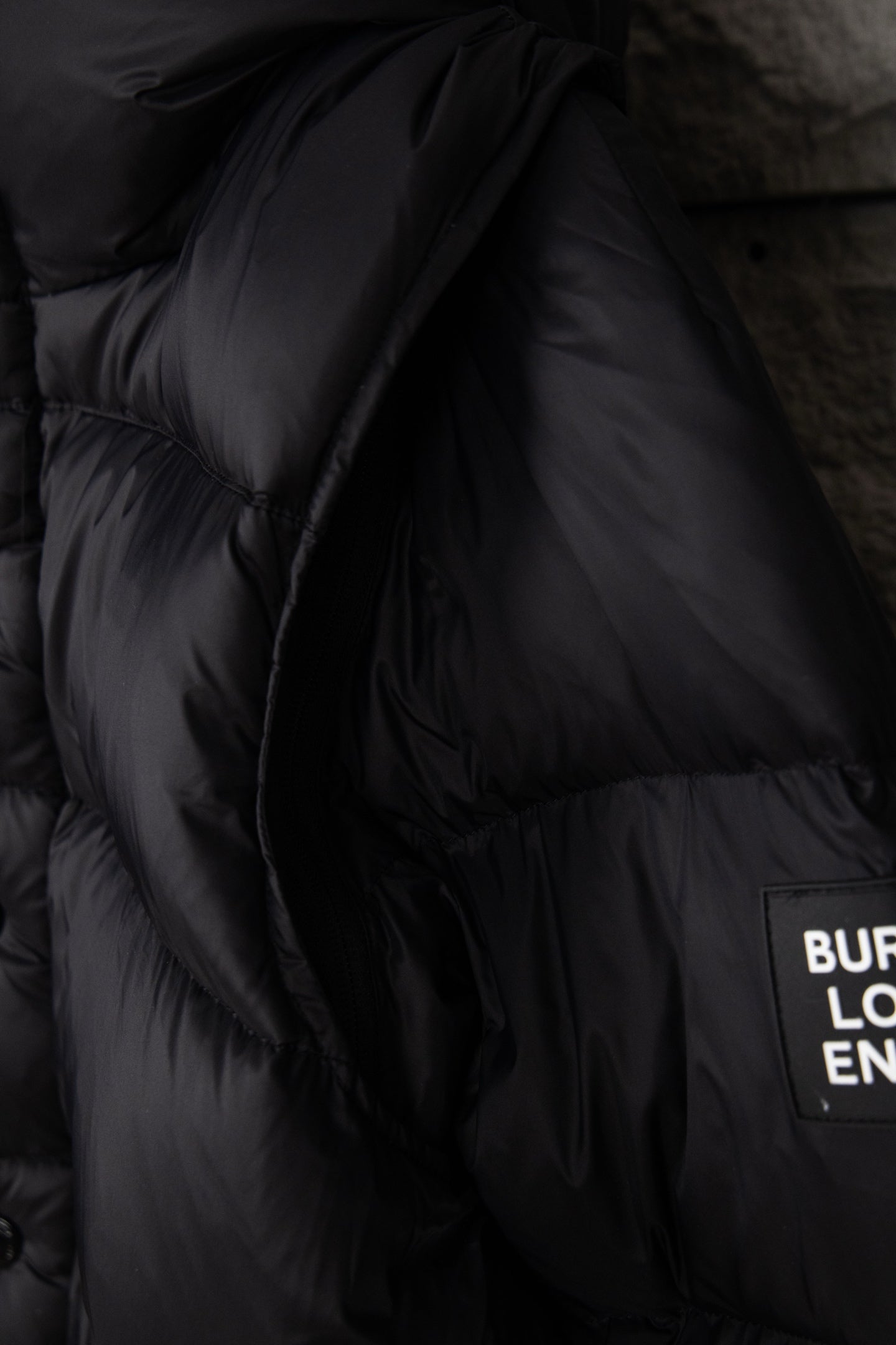 Black puffer jacket sleeve with quilted stitching and small logo label on the side